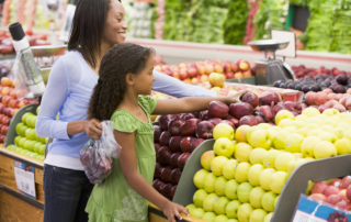 Mother and daughter selecting healthy fruit in produce section