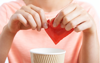 Woman uses artificial sweetener in coffee
