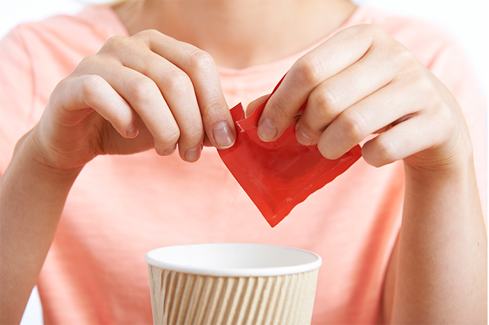 Woman uses artificial sweetener in coffee