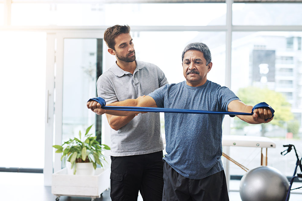 Senior man exercises and lifts weights during cardiac recovery supervised by doctor.