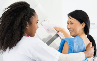 Happy woman looking at doctor while undergoing mammogram X-ray.