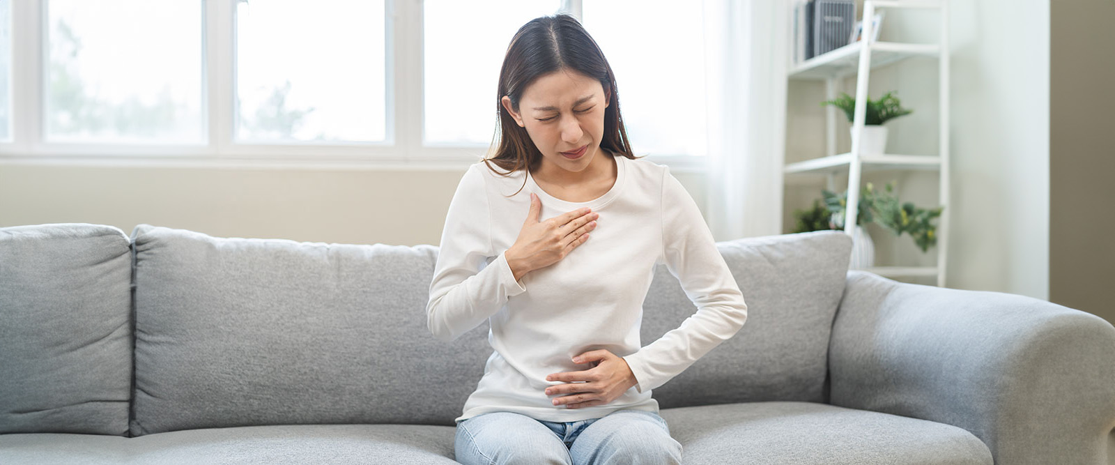 Young woman experiences pain of heartburn, GERD, and acid reflux after eating food.